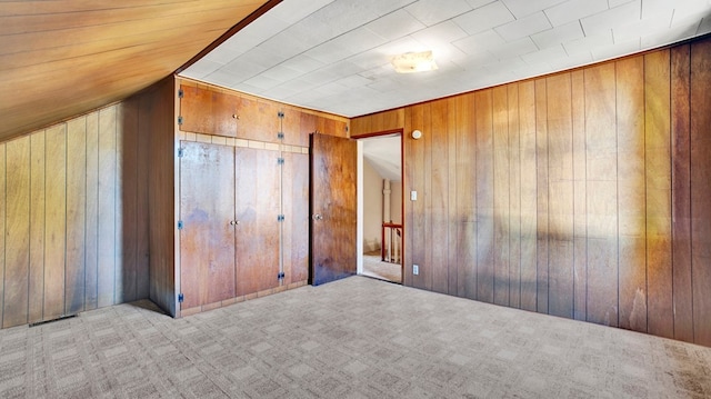 carpeted spare room featuring wooden walls