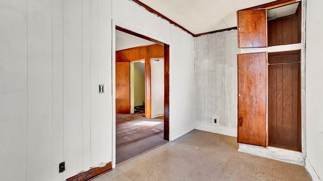 interior space featuring light colored carpet, crown molding, and wooden walls