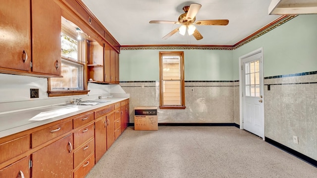 kitchen featuring ceiling fan, sink, and tile walls