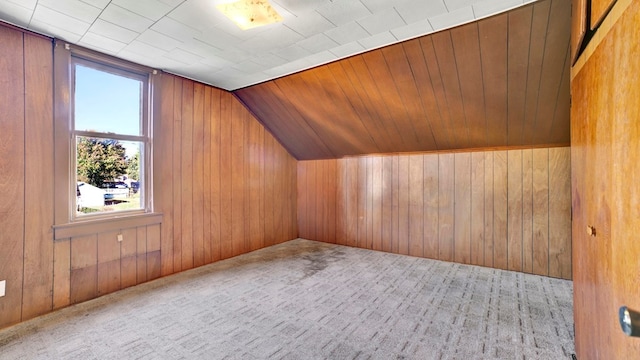 bonus room featuring wooden walls, light colored carpet, and vaulted ceiling