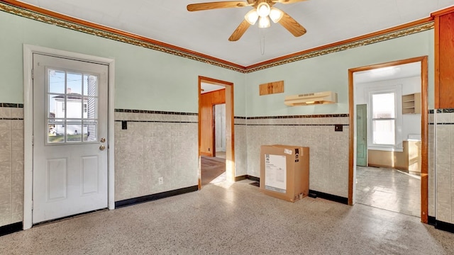 entrance foyer with ceiling fan, tile walls, and ornamental molding