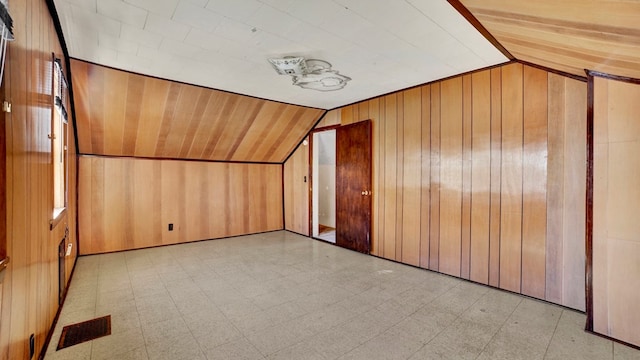 additional living space featuring lofted ceiling and wood walls