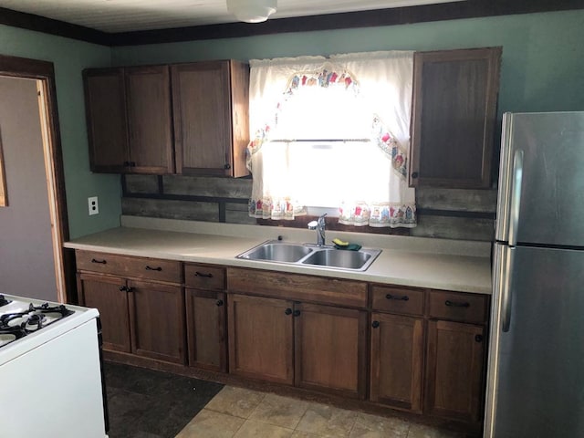 kitchen featuring sink, white gas stove, and stainless steel fridge