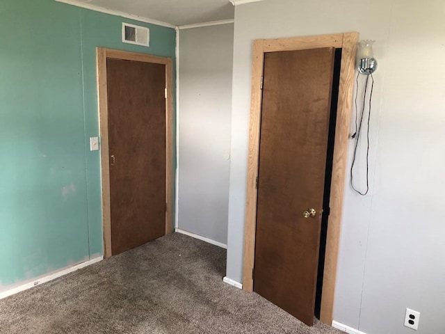 unfurnished room featuring dark colored carpet and ornamental molding