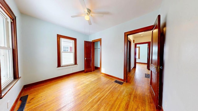 empty room featuring light wood-style floors, visible vents, ceiling fan, and baseboards