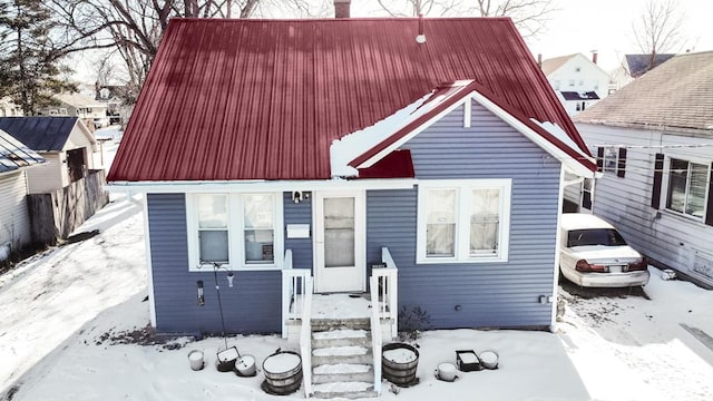 bungalow-style house featuring a chimney and metal roof