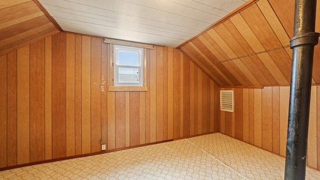 additional living space with lofted ceiling, wood walls, and baseboards