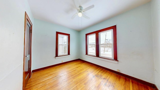 spare room featuring light wood-style floors, baseboards, and a ceiling fan