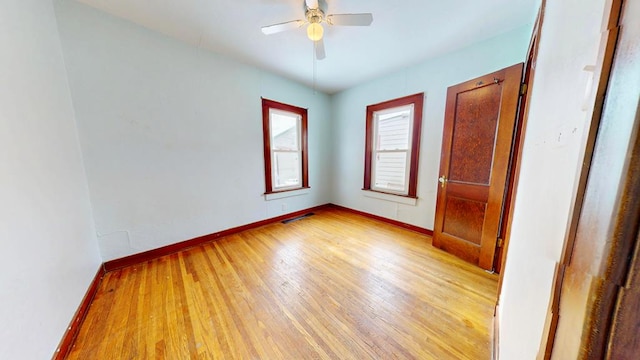 unfurnished room with visible vents, a ceiling fan, light wood-style flooring, and baseboards