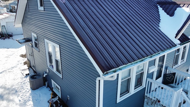 snow covered property with cooling unit and metal roof