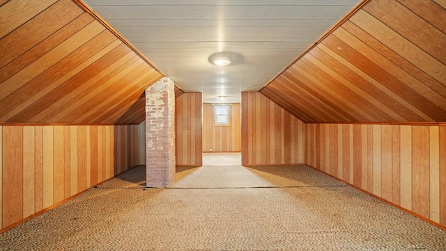 additional living space featuring carpet floors, lofted ceiling, and wood walls