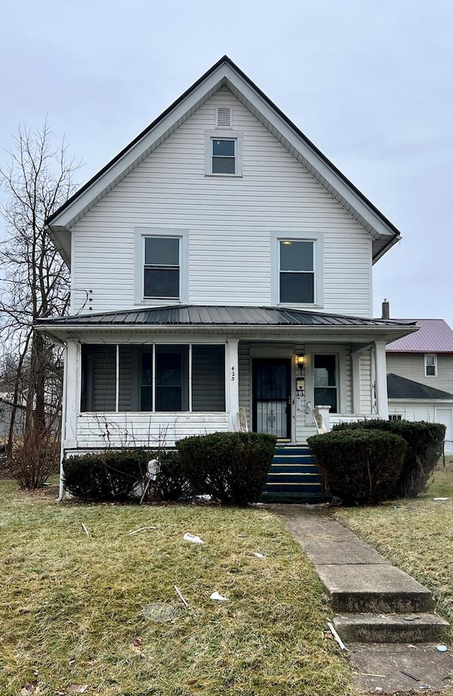 view of front of home with covered porch, metal roof, and a front yard