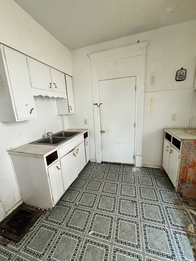 kitchen with dark floors, a sink, light countertops, and white cabinets