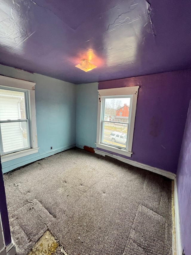 carpeted empty room featuring baseboards