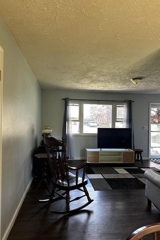 living room with a wealth of natural light, a textured ceiling, and wood finished floors
