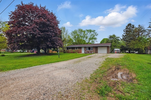 ranch-style house featuring a garage, a front lawn, and gravel driveway