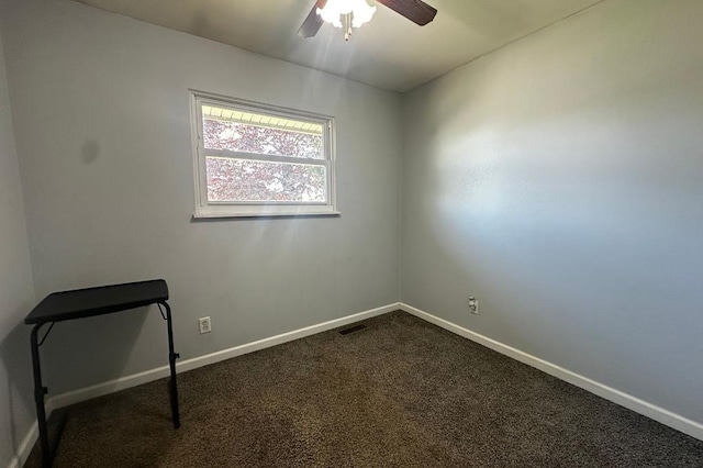 spare room featuring dark carpet, baseboards, ceiling fan, and visible vents