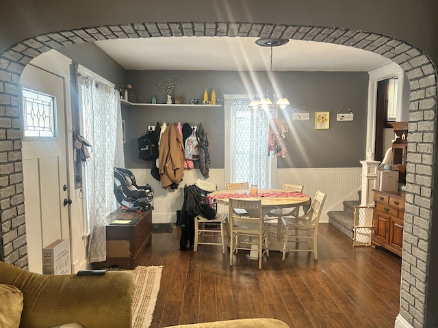 dining room with a chandelier, wooden walls, and dark hardwood / wood-style flooring