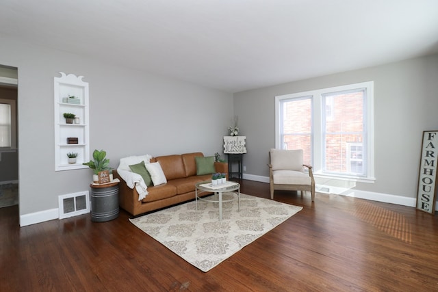 living room featuring dark hardwood / wood-style flooring and built in shelves