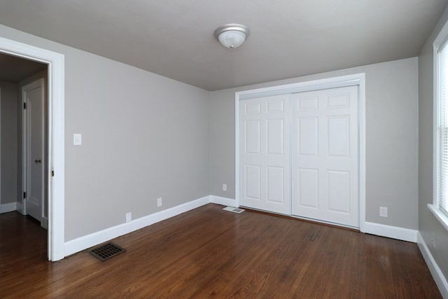 unfurnished bedroom with dark hardwood / wood-style floors and a closet