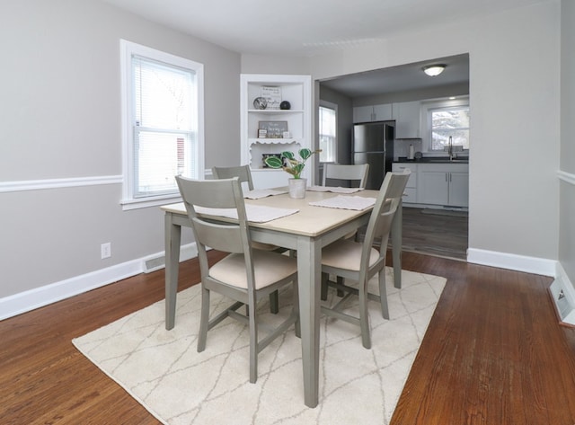 dining space featuring a healthy amount of sunlight, sink, built in features, and light wood-type flooring