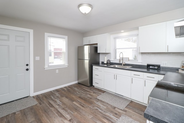 kitchen featuring dark wood-type flooring, sink, stainless steel fridge, white cabinets, and backsplash