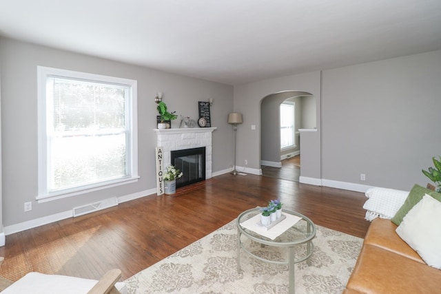 living room featuring dark hardwood / wood-style flooring and a stone fireplace