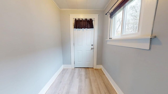 doorway with baseboards, ornamental molding, and light wood finished floors