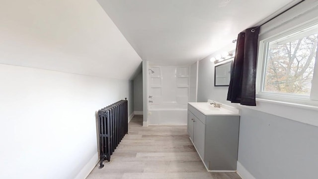 full bathroom with radiator heating unit, vaulted ceiling, wood finished floors, a washtub, and vanity