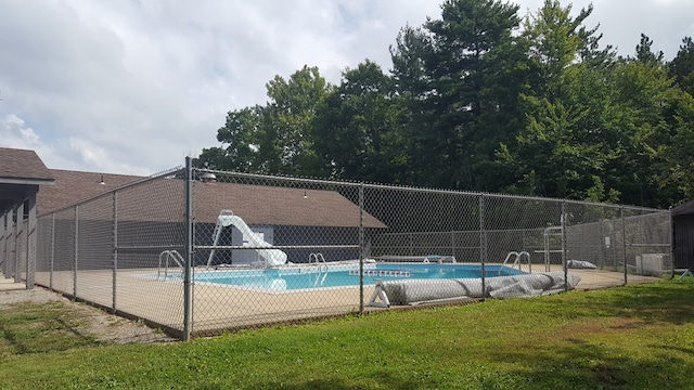 view of swimming pool with a fenced in pool, a water slide, fence, and a lawn