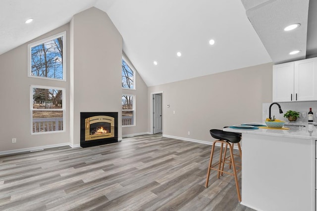 kitchen featuring light countertops, decorative backsplash, light wood-style floors, white cabinetry, and baseboards