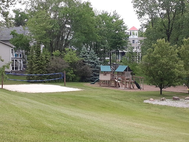 surrounding community with playground community, a lawn, and volleyball court