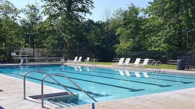 pool with a patio area and fence