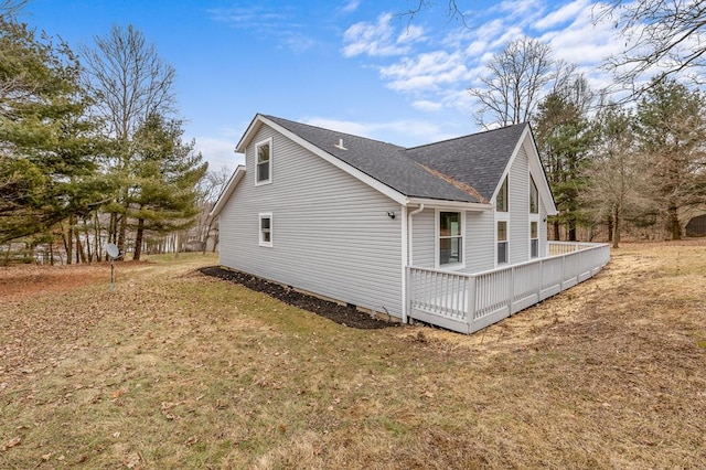 view of side of property with a shingled roof, a lawn, and a wooden deck