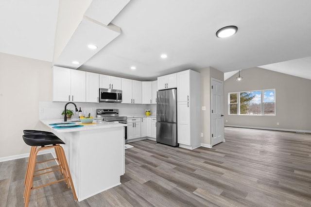 kitchen featuring a peninsula, light wood-style floors, appliances with stainless steel finishes, and light countertops