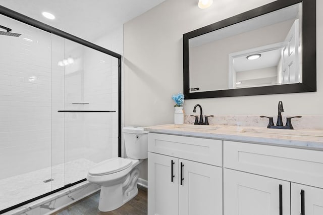 bathroom featuring double vanity, a stall shower, a sink, and toilet