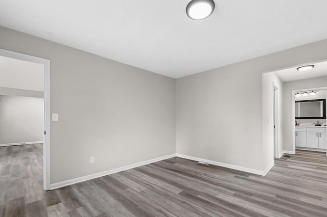 spare room featuring a sink, baseboards, and wood finished floors