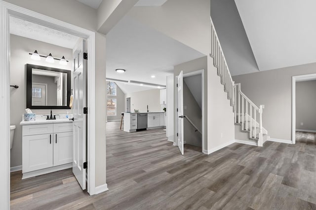 interior space featuring wood finished floors, vaulted ceiling, and stairs