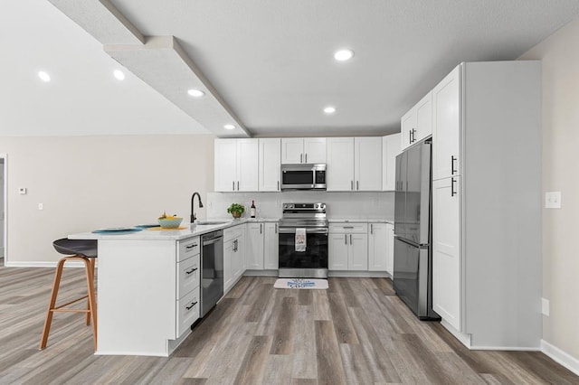 kitchen featuring a peninsula, appliances with stainless steel finishes, white cabinets, and a sink