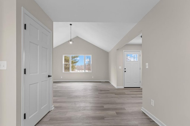 entryway with light wood-style floors, lofted ceiling, and baseboards