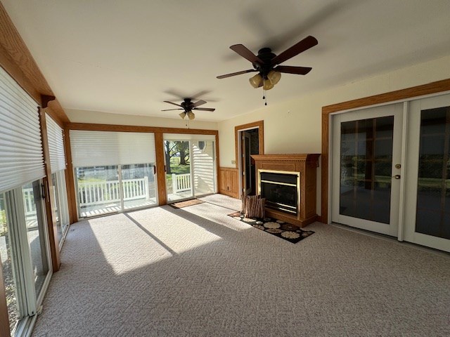 unfurnished living room with light carpet, french doors, and ceiling fan