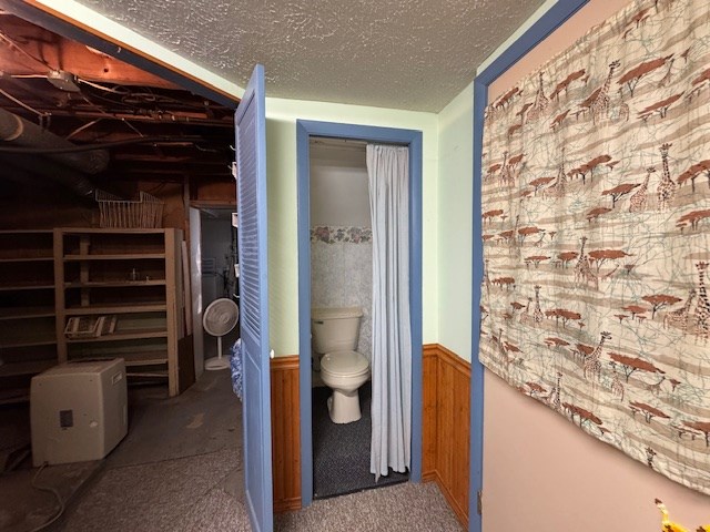 corridor featuring wood walls and a textured ceiling