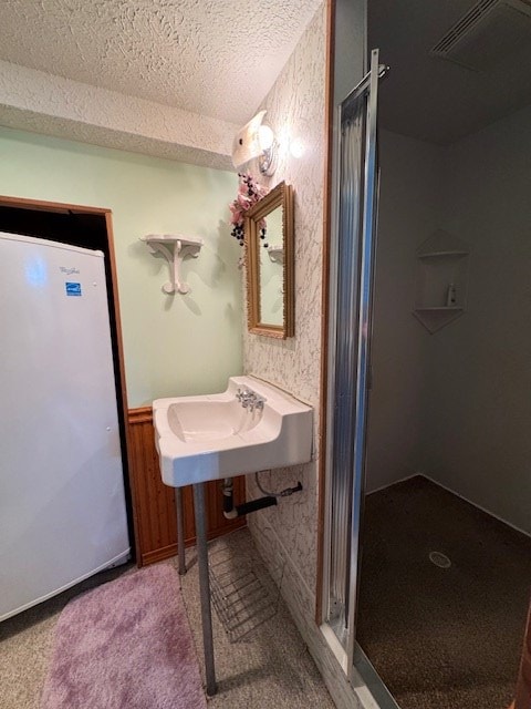 bathroom with a textured ceiling, sink, and walk in shower