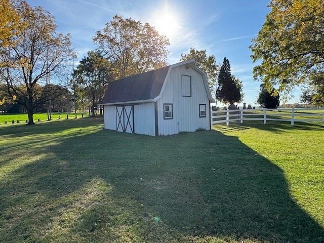 view of outbuilding featuring a rural view and a lawn