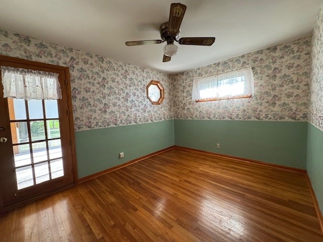 empty room featuring wood-type flooring, ceiling fan, and a healthy amount of sunlight