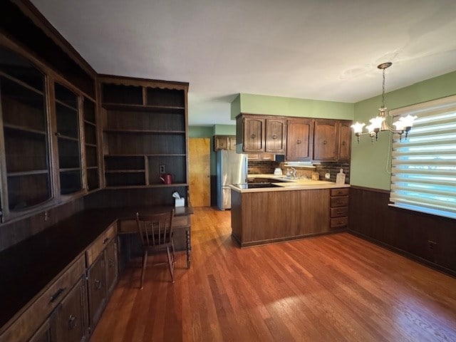 kitchen featuring kitchen peninsula, stainless steel fridge, pendant lighting, a chandelier, and dark hardwood / wood-style floors