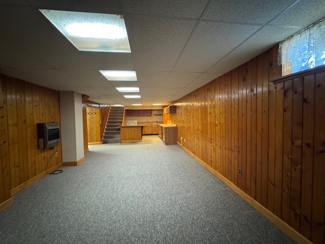 basement with carpet floors, heating unit, and wood walls