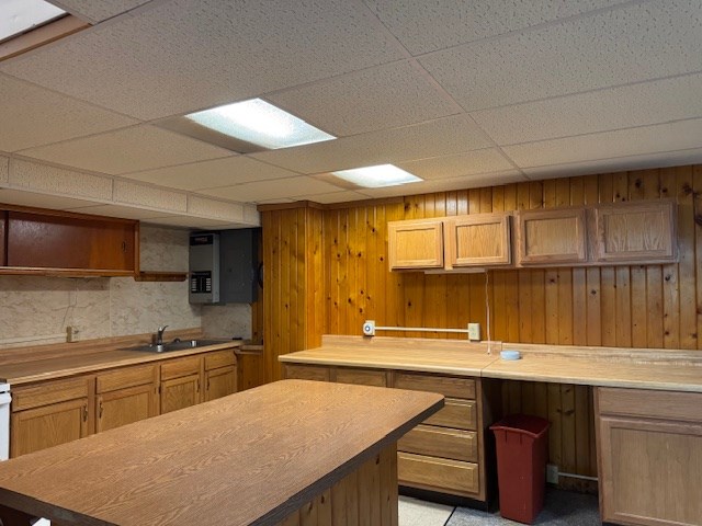 kitchen featuring a drop ceiling, wood walls, and sink