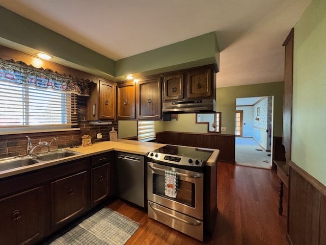 kitchen featuring sink, dark hardwood / wood-style floors, dark brown cabinetry, kitchen peninsula, and stainless steel appliances