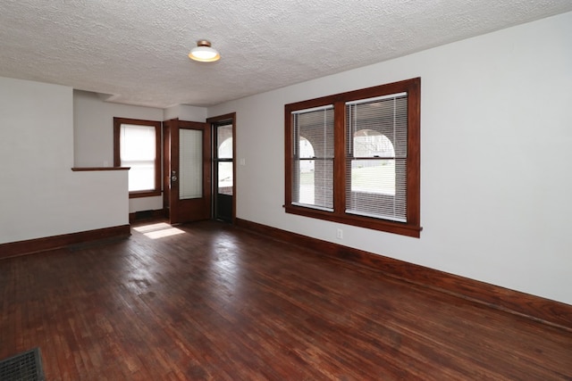 spare room with visible vents, a textured ceiling, baseboards, and wood finished floors